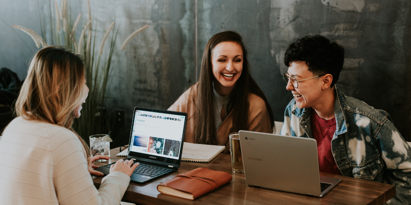 three friends laughing and planning in a cafe