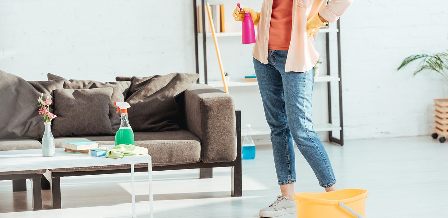 Lady holding pink spray bottle cleaning her living room